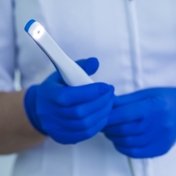 Two gloved hands holding a thin white intraoral camera