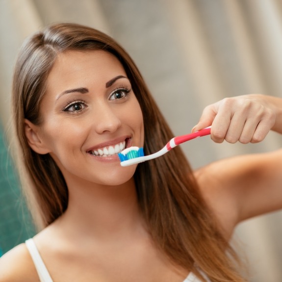 Woman smiling while brushing her teeth