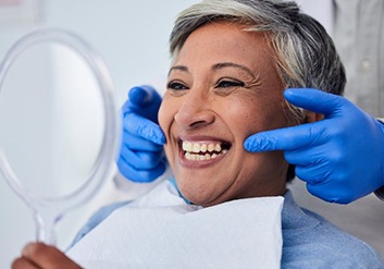 a patient checking her teeth with a mirror