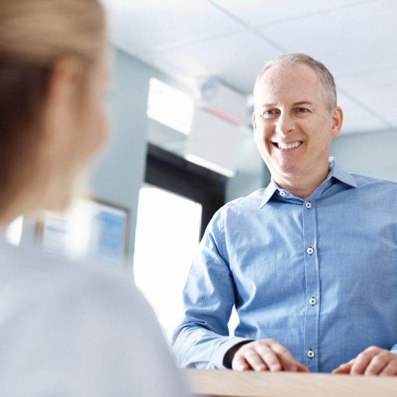 Man talking to dental team member at front desk