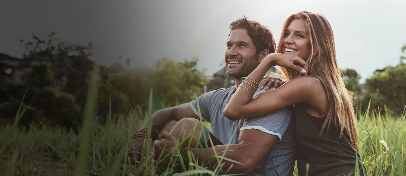 Smiling man and woman sitting in grass together