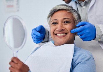 a patient checking her teeth with a mirror