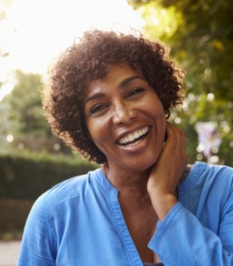 Older woman in blue blouse grinning outdoors