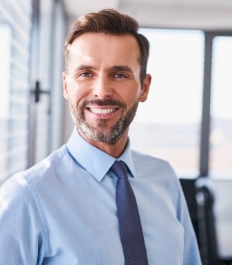 Man in dress shirt and tie smiling in an office