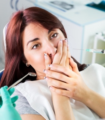 Woman in dental chair covering her mouth with her hand
