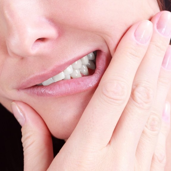 Close up of person holding their jaw in pain before tooth extractions in Cranford